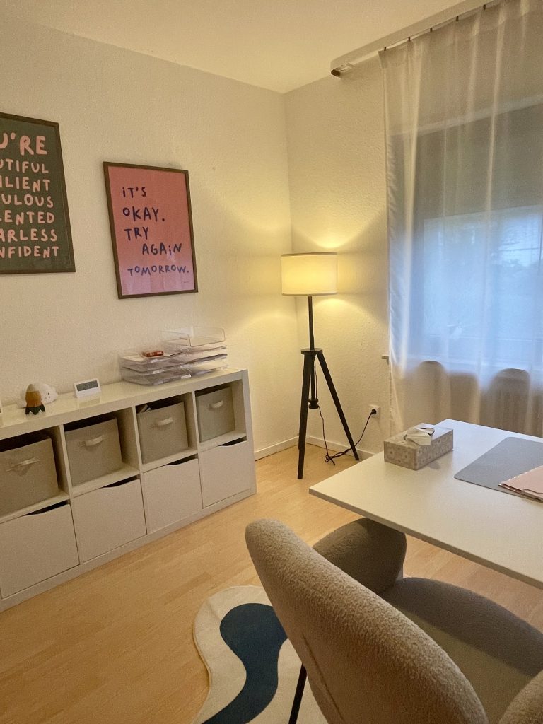 Ein anderer Blickwinkel aus dem 2. Behandlungszimmer; zu sehen ist ein Stuhl, eine Lampe und ein Regal